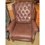 A brown leather effect wing back arm chair