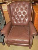 A brown leather effect wing back arm chair