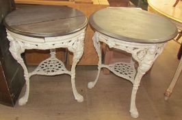 A pair of cast iron pub tables with circular wooden tops,