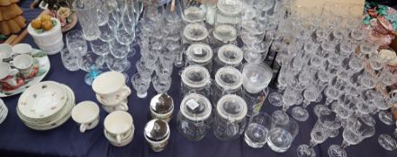 A suite of crystal glasses together with glass storage jars, vases,