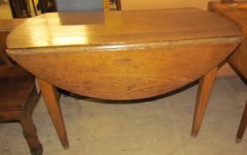 An oak drop leaf table of oval form,