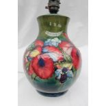 A Moorcroft pottery table lamp of baluster form, decorated in the orchid pattern to a green ground,