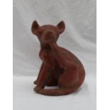 A pre-Columbian type dog, seated scratching under his chin with its back leg,