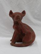 A pre-Columbian type dog, seated scratching under his chin with its back leg,