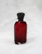 An Edwardian Silver topped and cranberry glass scent bottle, cast with leaves to a faceted body,