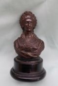A bronze head and shoulders portrait bust, on a turned wooden base,