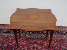 An Edwardian rosewood Pembroke table with a serpentine shaped top with drop flaps and a central