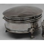 A silver trinket box of circular plain form with moulded borders, on three trefoil supports,