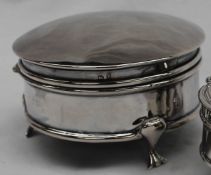 A silver trinket box of circular plain form with moulded borders, on three trefoil supports,