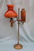 A Brass and glass oil lamp, with an orange glass shade and brass column on a spreading foot,