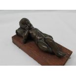 A bronze model of a recumbent cupid, with his head resting on a pillow,