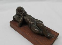 A bronze model of a recumbent cupid, with his head resting on a pillow,