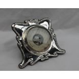 An Art Nouveau inspired silver desk barometer, with a ribbon border, with a central paper dial,