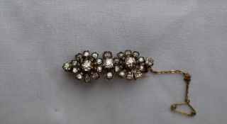 An early 20th century diamond set bar brooch of floral form set with cushion cut and old round cut