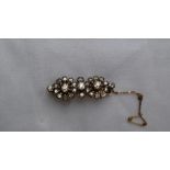 An early 20th century diamond set bar brooch of floral form set with cushion cut and old round cut