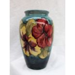 A Moorcroft pottery hibiscus pattern vase with a tapering blue body and pink and yellow flowers,