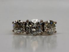 A three stone diamond ring, set with old round cut diamonds, the centre stone approximately 1.