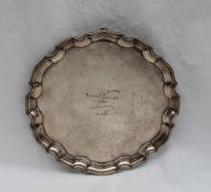 A George VI silver salver, with a shaped edge on three scrolling feet,