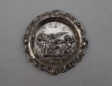 A continental white metal dish of circular form, embossed with swans and cherubs,