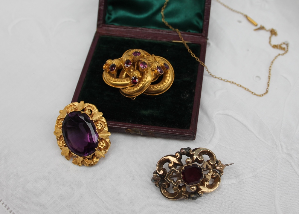 A Victorian brooch, set with a central faceted amethyst in a yellow metal mount,