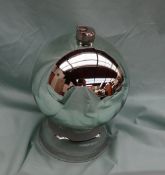 A silvered witches ball, with a white metal suspension hook, on a glass stand,