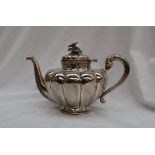 A Mexican white metal teapot of lobed tapering shape, the lid with a floral surmount,