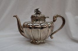 A Mexican white metal teapot of lobed tapering shape, the lid with a floral surmount,