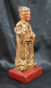 A Chinese carved, gilt and red painted figure of a dignitary on a square base,