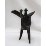 A Chinese bronze Jue wine vessel, the spout and body with raised decoration on tripod legs,