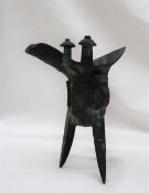 A Chinese bronze Jue wine vessel, the spout and body with raised decoration on tripod legs,