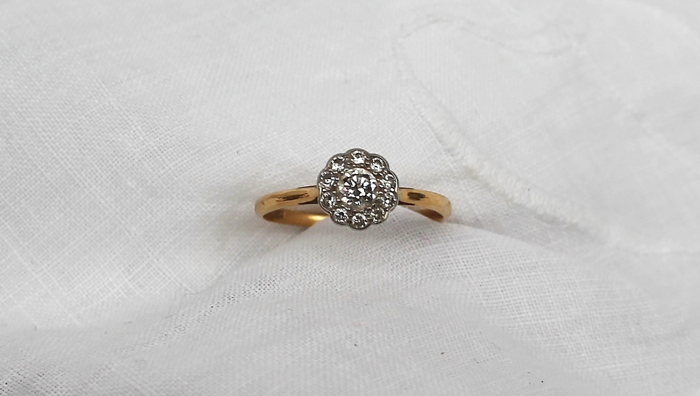 A diamond cluster ring, with a central round brilliant cut diamond approximately 0.