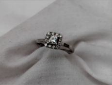 A diamond cluster ring, in the halo style with a central princess cut diamond, approximately 0.