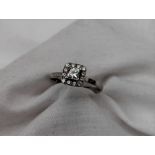 A diamond cluster ring, in the halo style with a central princess cut diamond, approximately 0.