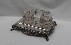 A late Victorian silver desk standish, with a shell leaf and dart border on four claw feet,