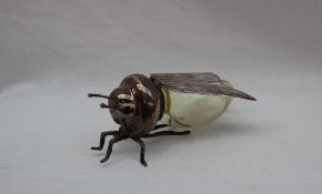 A yellow glass and white metal table salt, in the form of a flying insect,