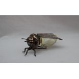 A yellow glass and white metal table salt, in the form of a flying insect,