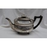 A George III silver teapot of oval shape with a flower and leaf border on ball feet, London, 1810,