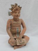 A pre-Columbian type figure seated cross legged, the hat adorned with an animal mask and arms,