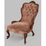 A VICTORIAN MAHOGANY LOW ARMCHAIR, the scalloped back with a floral carved crest above deep button