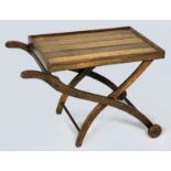 A VICTORIAN OAK PICNIC TABLE, the slatted top above a folding X-frame with two wooden wheels, (