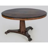A WILLIAM IV WALNUT DINING TABLE, the quartered circular top above an ebonized moulded frieze,
