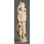 A FINELY CARVED IVORY GUARDIAN FIGURE, FIRST HALF OF THE 20th CENTURY, holding a sword entwined with