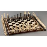TWO IVORY SETS OF CHESSMEN AND A BOARD, * An ivory set carved as a rajah and his wife with camels,