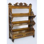 A LATE VICTORIAN MAHOGANY DISPLAY RACK, the top with a broken-arch pediment above two shelves with