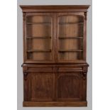 A VICTORIAN MAHOGANY BOOKCASE-ON-CABINET, the moulded pediment above two arched glazed doors,