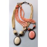 A SILVER AND CORAL NECKLACE, composed of an oval and bead framed coral pendant, flanked by three