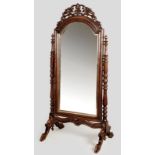 AN EDWARDIAN MAHOGANY DRESSING MIRROR, the rectangular bevelled plate with arched carved top mounted