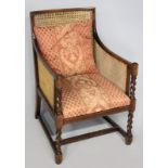 A MAHOGANY BERGERE CHAIR, the caned back and sides with upholstered cushions above a patterned