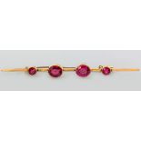 A 15CT YELLOW GOLD AND PINK TOURMALINE BAR BROOCH, the large tourmalines tube-set flanked by two