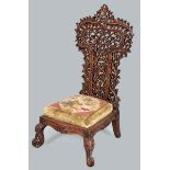 AN INDONESIAN CARVED HARDWOOD CHAIR, the ornately latticed back above an upholstered cushion, carved